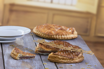 Galette des Rois cake . Traditional French Epiphany cake with almond on grey wooden board against window background.