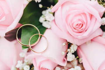 Two elegant gold rings for the wedding of lovers with scenery from fresh roses. 