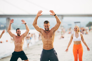Group young attractive people having fun on beach and doing some fitness workout.