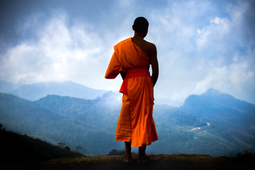 The young Thai monk standing over landscape in Thailand. - obrazy, fototapety, plakaty
