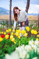 Naklejka na ściany i meble beautiful woman with tulips flowers in garden