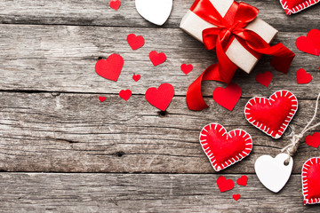Valentines day background. Red hearts, ribbon, and gift box on wooden background.