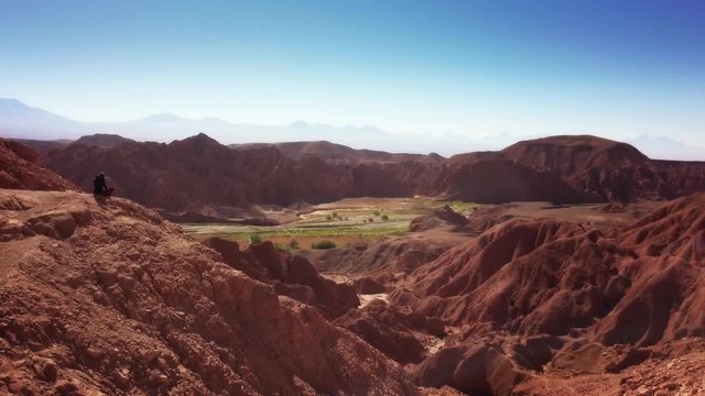 Aerial shot of female trekker standing at the cliff contemplating the horizon of the Atacama desert. 4k