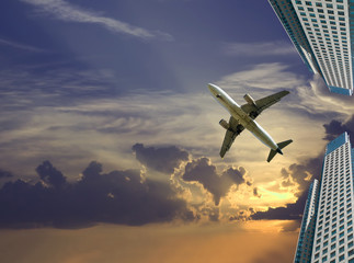 Fototapeta na wymiar airliner in sky on skyscrapers background
