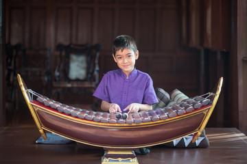 Little asian Thai boy playing alto xylophone music performance in ceremony