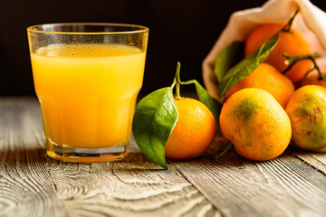 Glass of fresh juice and mandarins on table