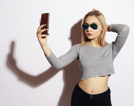 Pretty hipster girl making selfie over white background.