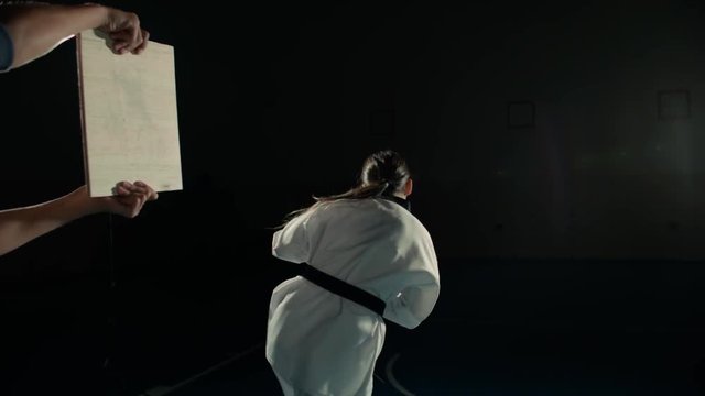Asian beautiful girl fighter practicing to break the board with a kick of the feet, slow motion