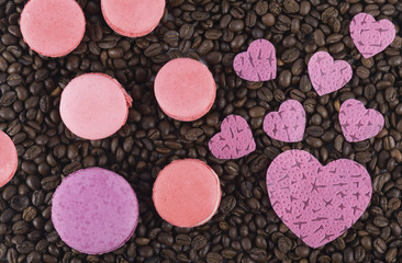 on the background of coffee beans, chocolate macaroni pastry with pink hearts of love