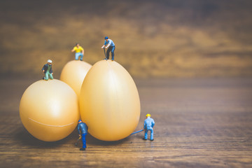 Miniature people work at Easter-eggs for Easter day