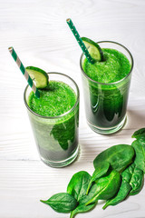Smoothie of spinach and cucumber on a white wooden background