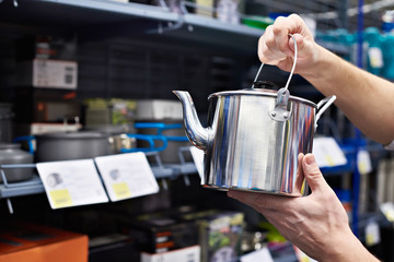 Camp pot and kettle in hands of buyer in shop