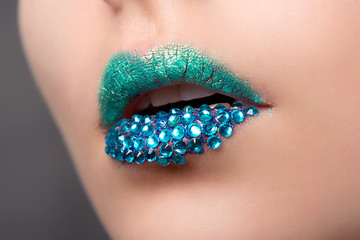 Glamorous lip with a very bright lipstick blue colors and rhinestones close-up