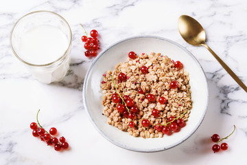 Healthy breakfast of muesli and glass of milk with red currant decor on grey marble table. Selective focus 