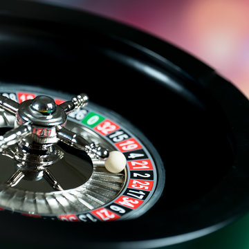 High contrast image of casino roulette and poker chips on bokeh background.