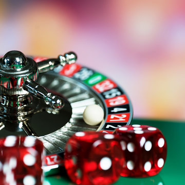 High contrast image of casino roulette and poker chips on bokeh background.