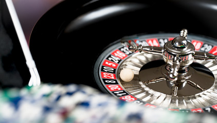 Fototapeta na wymiar High contrast image of casino roulette and poker chips on bokeh background.