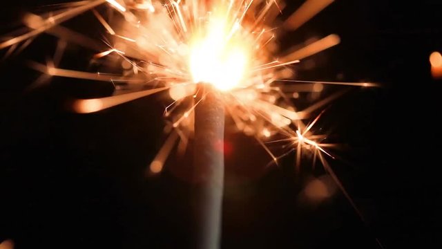 brennende Wunderkerze in Nahaufnahme mit schwarzem Hintergrund