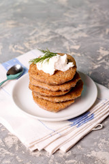 Delicious homemade potato pancakes on plate with sour cream