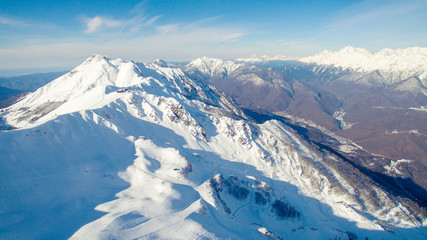 now-capped mountain slopes on  sunny day aerial view