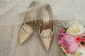 Obraz na płótnie Canvas Golden bridal shoes are covered with a veil. Wedding details. 