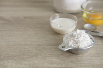 FULL OF BAKERY INGREDIENTS
Important bakery ingredients, white flour in a measuring cup, flour jar, milk and eggs in transparent cups with measuring spoon.