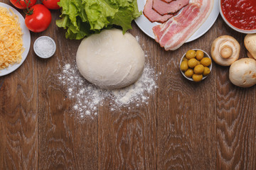 Tomatoes, cheese, olives, lettuce, salt, bacon, ham, tomato paste, champignons, dough and flour. Ingredients for pizza top view