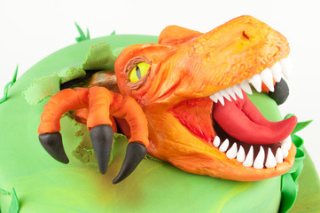 Art cake with orange dinosaur, decorated with green leaves. Gift for the boy. Picture for a menu or...