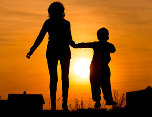 Silhouette of Mom and son in the rays of sunset