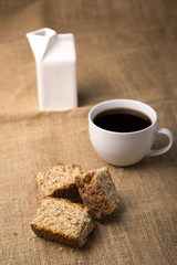 Cup of coffee with rusks and milk jug high