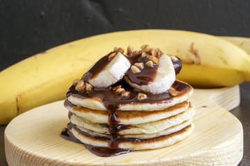 Pile of pancakes with banana and chocolate sauce.