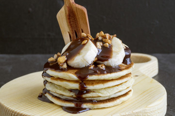 Pile of pancakes with banana and chocolate sauce.