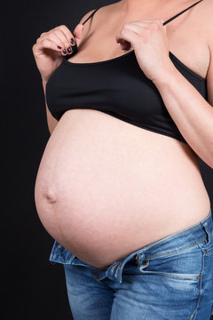 a pregnant woman in bras and jeans