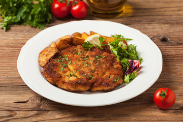 Chicken schnitzel, served with roasted potatoes and salad.