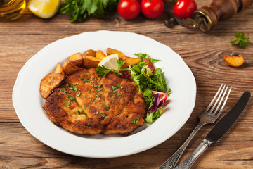Chicken schnitzel, served with roasted potatoes and salad.