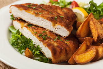 Chicken schnitzel, served with roasted potatoes and salad.