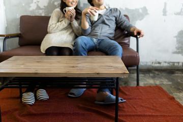 Naklejka premium テレビを見ながらコーヒーを飲む若い夫婦