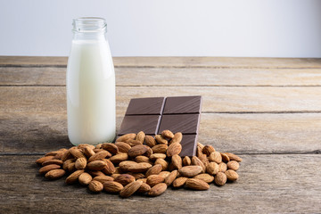 milk in bottle, chocolate and almond on wooden
