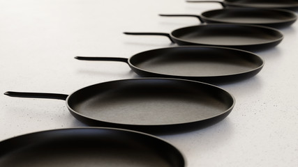 Linear Array of Iron Frying Pans on a Light Gray Surface