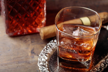 Glass of  whiskey and cigar on old wooden table.