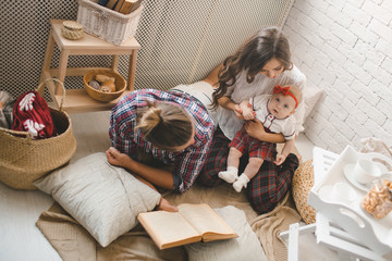 Happy young family mother, father and daughter playing on carpet at home.