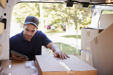 Courier With Digital Tablet Checking Packages In Van - Powered by Adobe