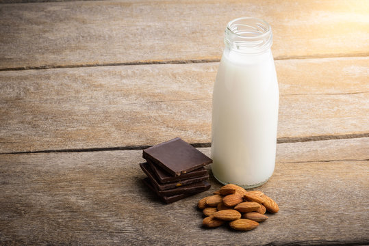 milk in bottle, chocolate and almond on wooden