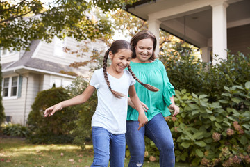 Grandmother Playing Soccer In Garden With Granddaughter