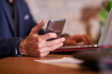 Closeup view of a businessman while using a smartphone in office environment.