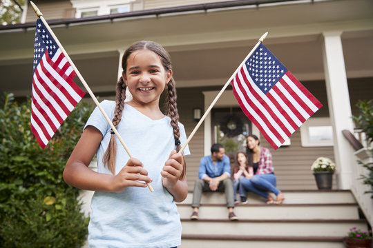 Portrait Of Girl Outside Family Home Holding American Flags