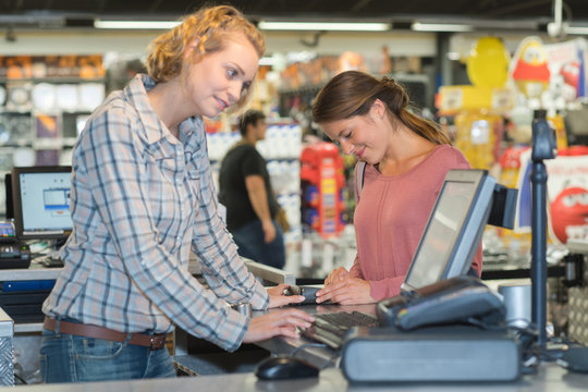 female customer paying at cash desk with terminal in supermarket