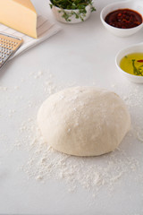 Raw dough for pizza with ingredients.