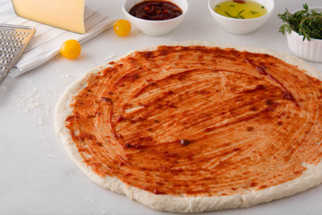 Raw dough for pizza with ingredients and spices on white background. Overhead with copy space.
