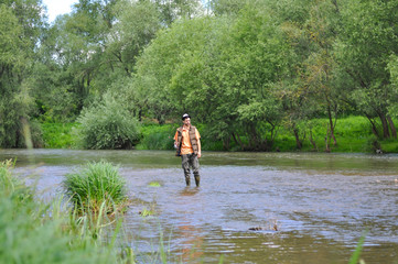Fototapeta na wymiar Man casts a hook on the river. Man fishing on wild river